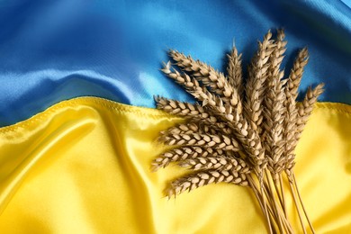 Ears of wheat on Ukrainian national flag, flat lay. Space for text