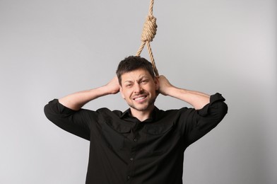Photo of Depressed man with rope noose on neck against light background