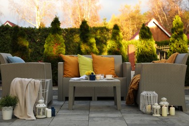 Photo of Beautiful rattan garden furniture, soft pillows and different decor elements in backyard