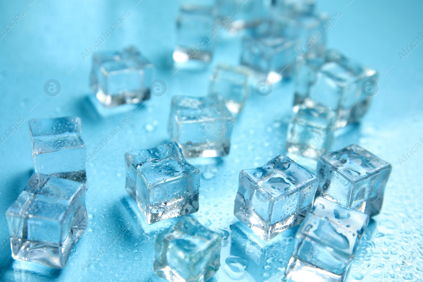 Photo of Ice cubes and water drops on turquoise background. Ingredient for refreshing drink