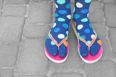 Photo of Woman wearing bright socks with flip-flops standing outdoors