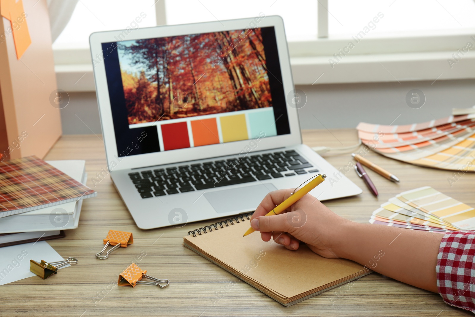 Photo of Female designer working at wooden table indoors, closeup