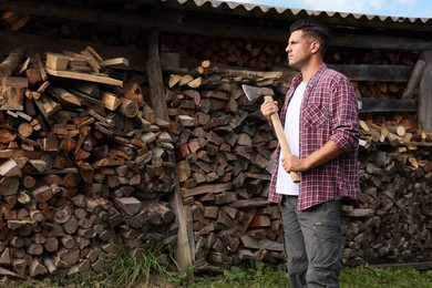 Man with ax near log pile outdoors