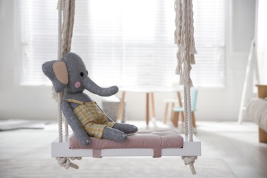 Photo of Beautiful swing with toy elephant in room. Stylish interior design