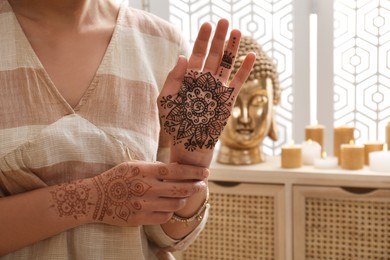 Photo of Woman with henna tattoo on hands indoors, closeup. Traditional mehndi ornament