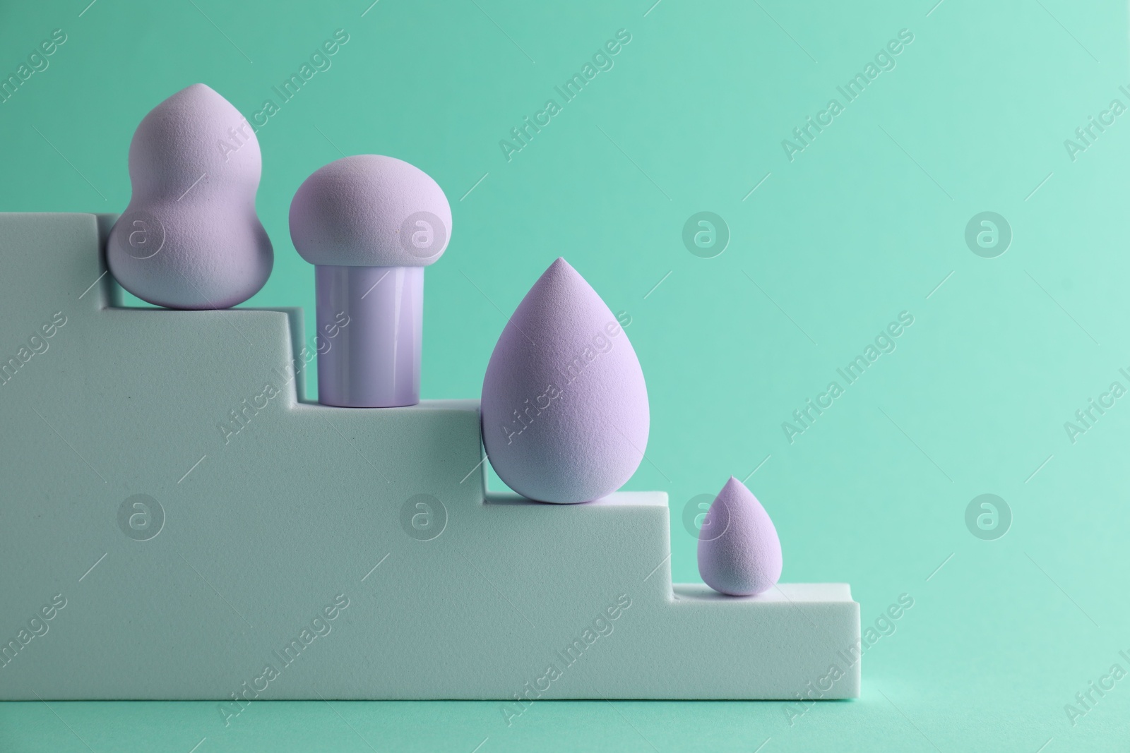 Photo of Stylish presentation of makeup sponges on turquoise background. Space for text