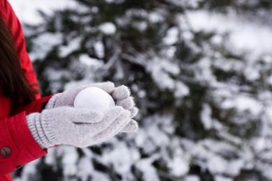 Young woman with snowball outdoors on winter day, closeup. Space for text