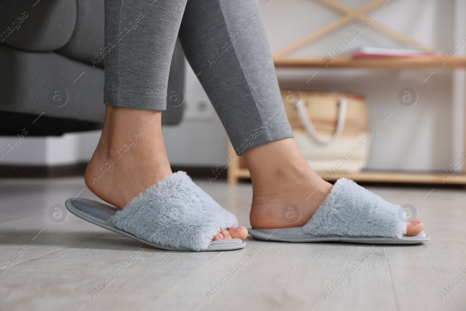 Photo of Woman wearing light blue soft slippers at home, closeup