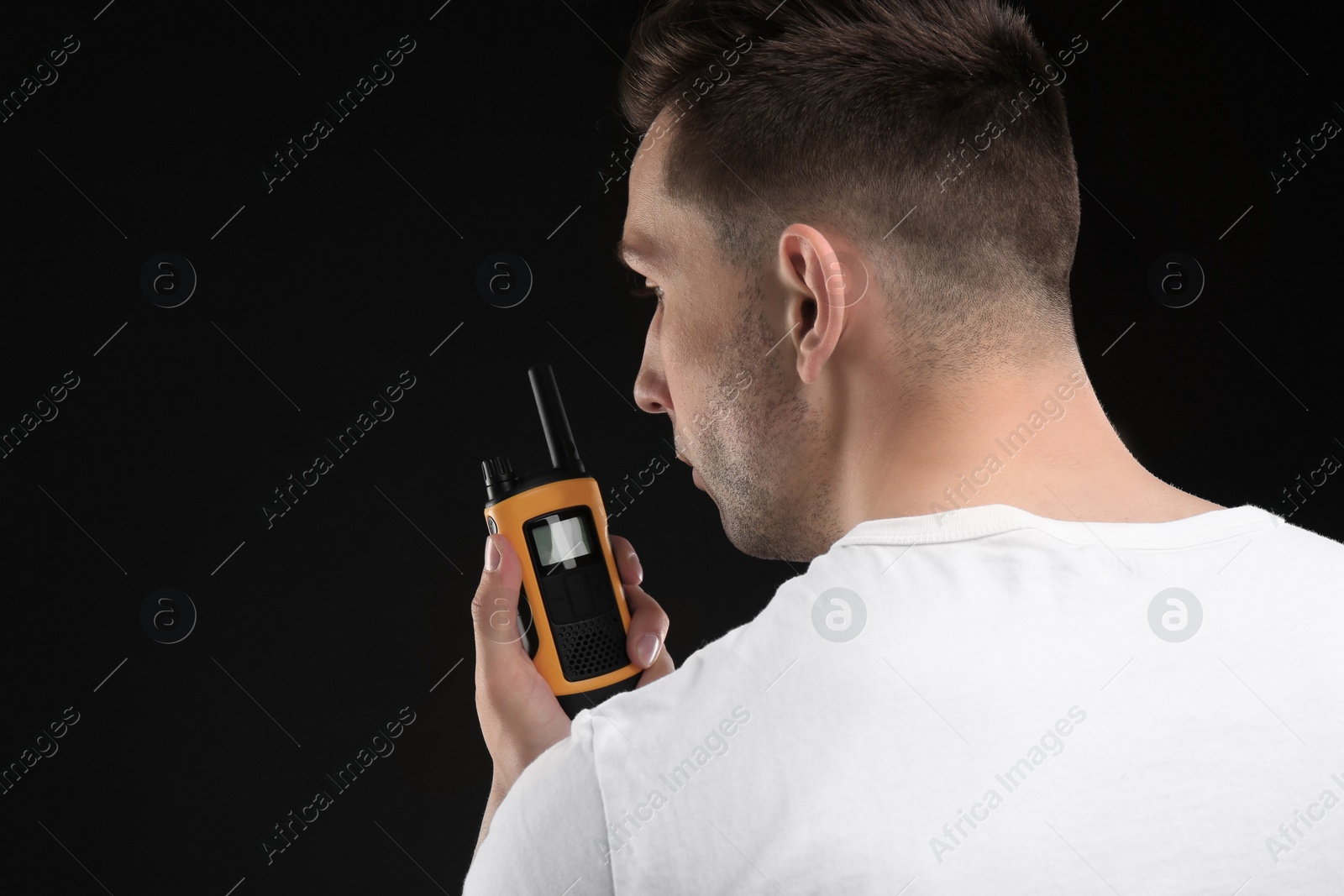 Photo of Male security guard using portable radio transmitter on dark background