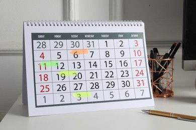 Photo of Timetable. Calendar with marked dates and stationery on white table indoors