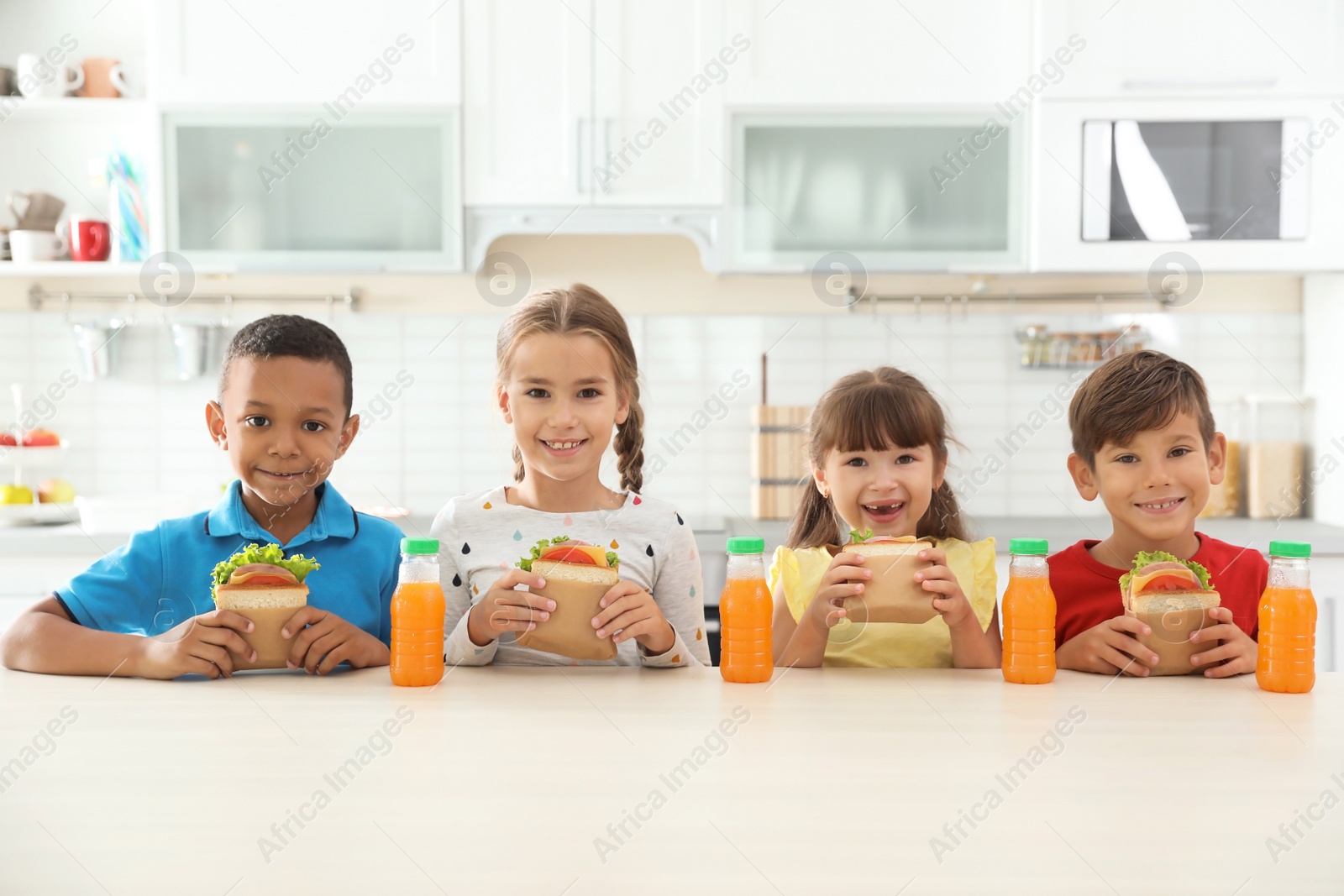 Photo of Children sitting at table and eating healthy food during break at school