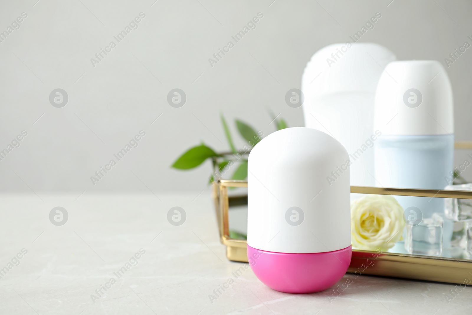 Photo of Female roll-on deodorants on white wooden table against grey background, space for text