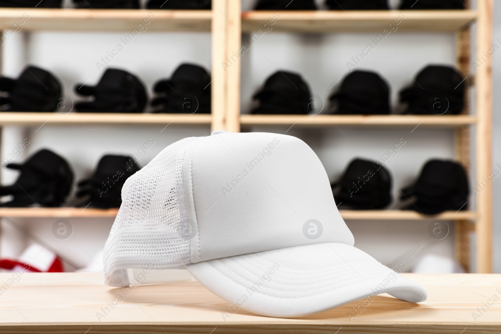 Photo of Blank white cap on wooden table in store. Mock up for design