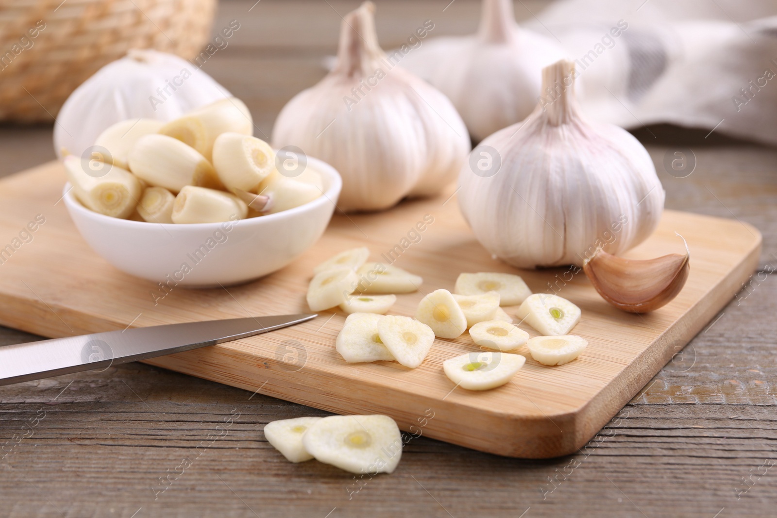 Photo of Aromatic cut garlic, cloves and bulbs on wooden table, closeup