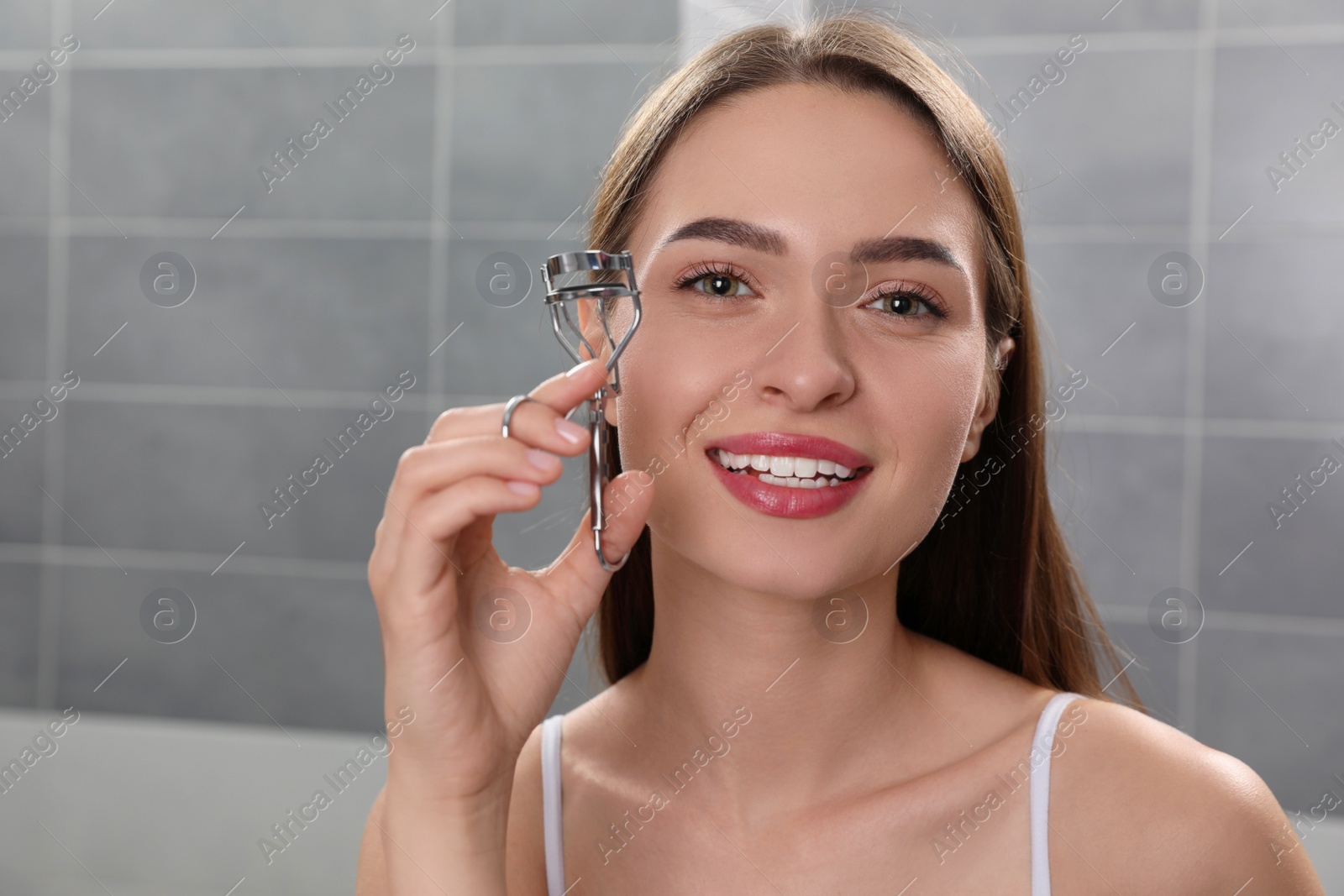Photo of Young woman with eyelash curler indoors, space for text