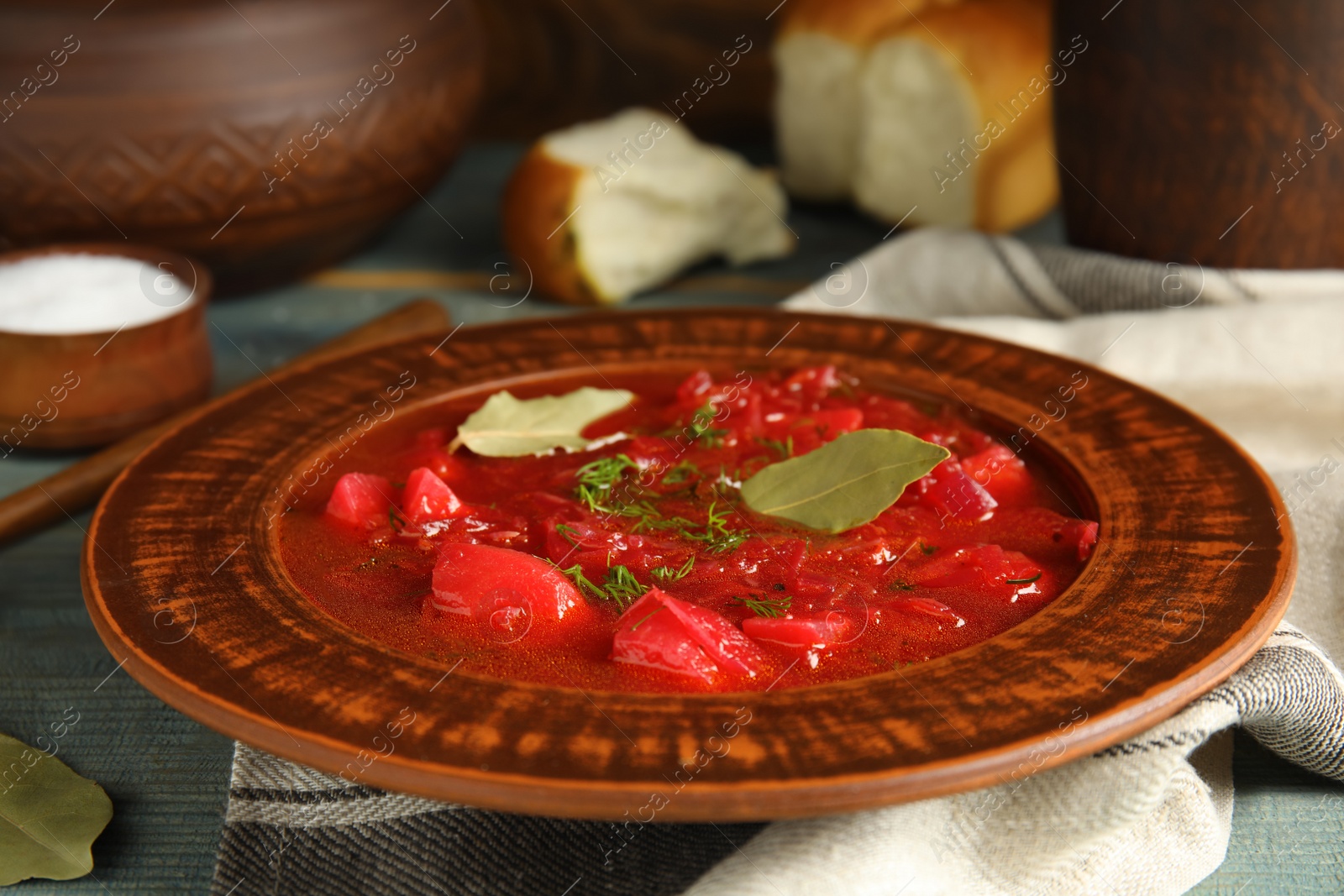 Photo of Stylish brown clay plate with Ukrainian borsch served  on wooden table