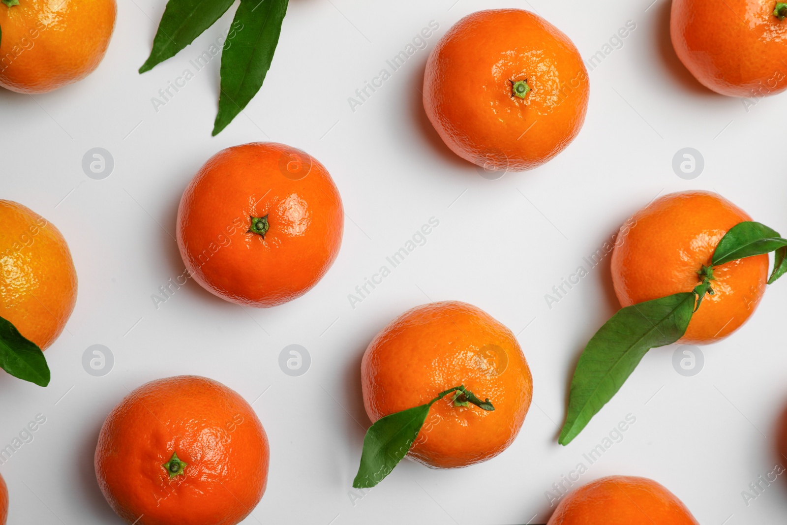 Photo of Delicious tangerines and green leaves on white background, flat lay