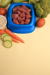 Photo of Raw meat in bowl and healthy products for pet on beige background, above view. Space for text