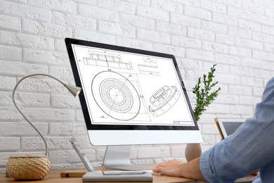 Male engineer working with technical drawing on computer indoors, closeup