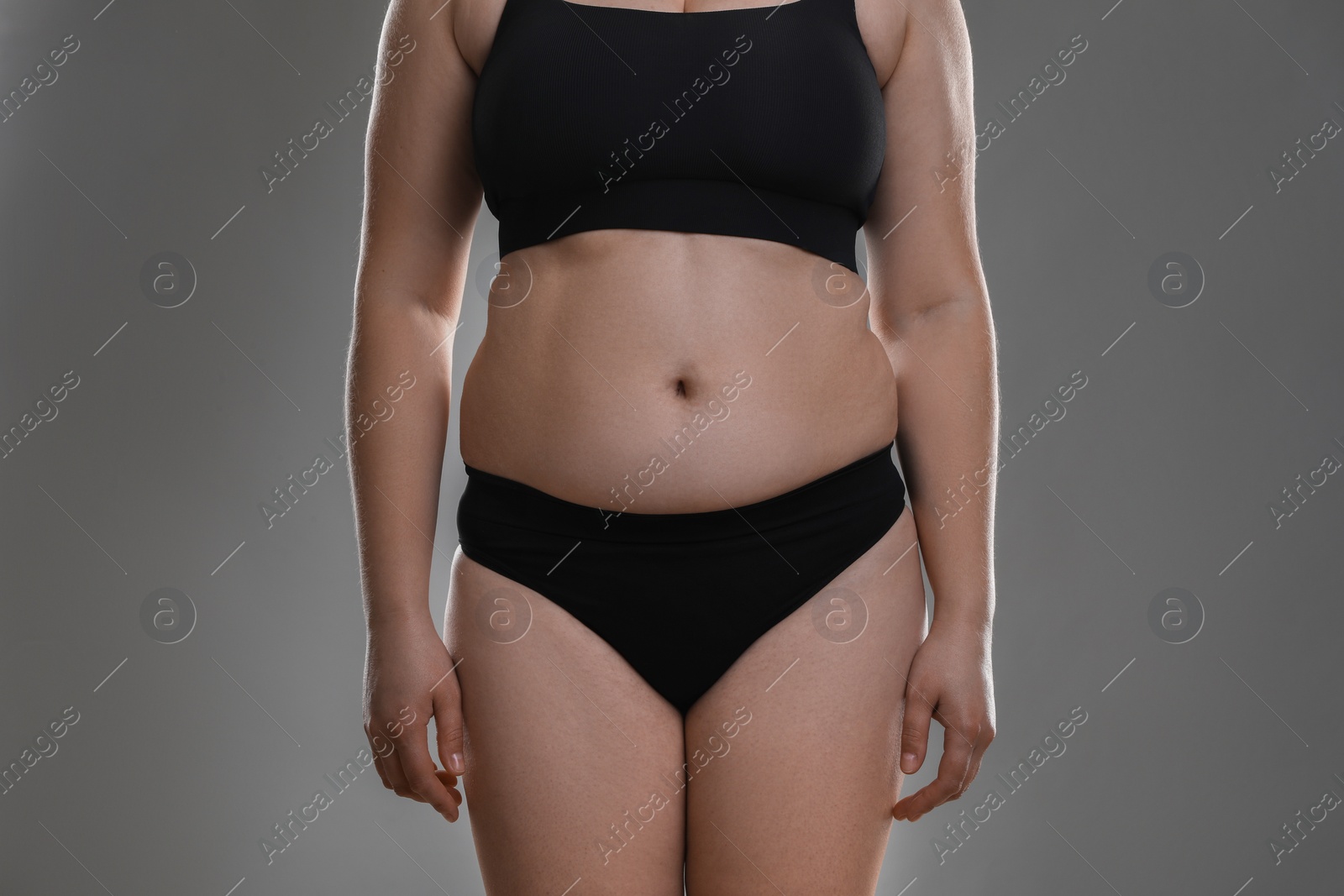 Photo of Woman with excessive belly fat on grey background, closeup. Overweight problem