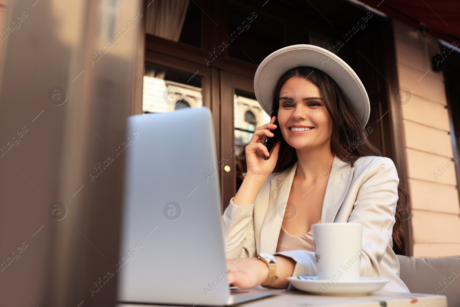Photo of Beautiful young woman talking on phone in outdoor cafe