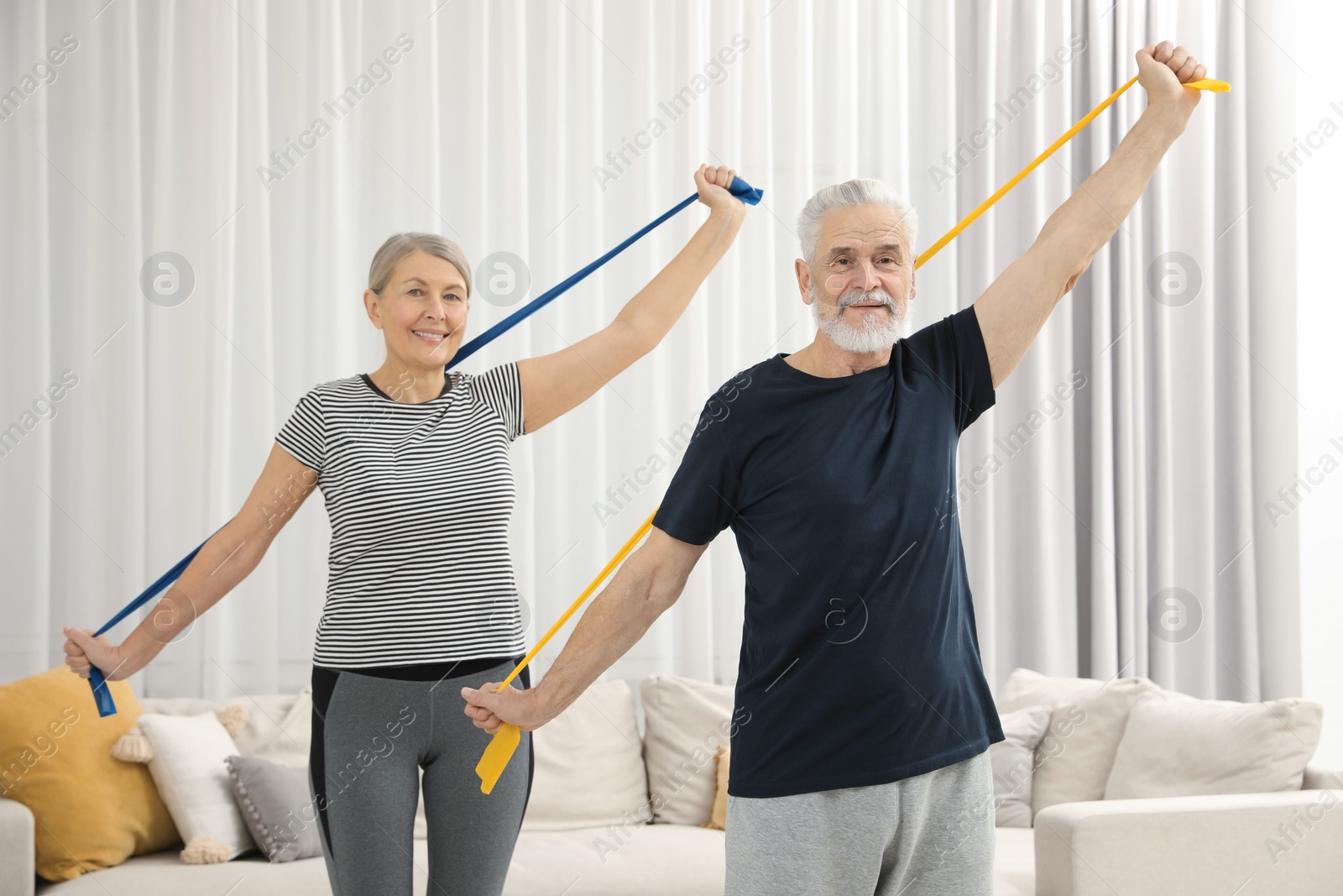 Photo of Senior couple doing exercise with fitness elastic bands at home