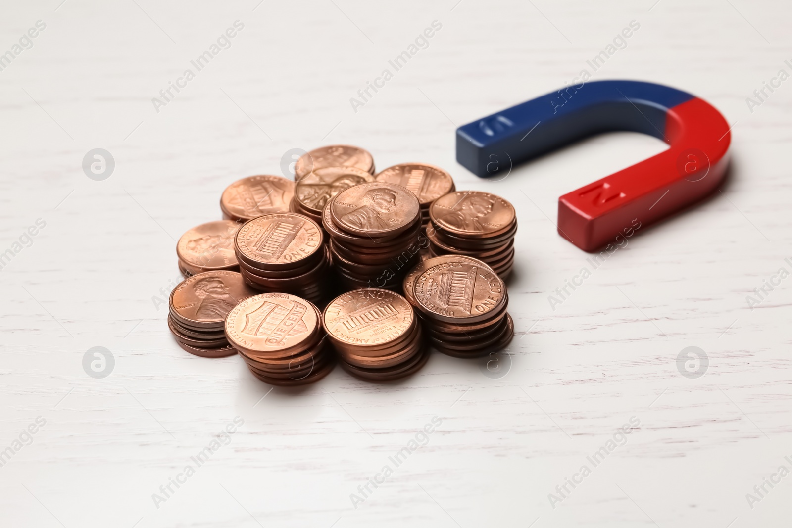 Photo of Magnet attracting coins on wooden background. Business concept