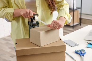 Photo of Seller packing cardboard box in office, closeup
