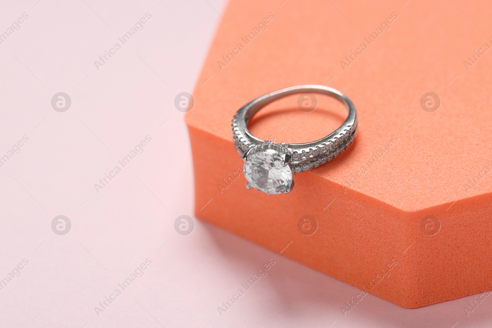 Photo of Beautiful ring with gemstones on light background, space for text. Luxury jewelry