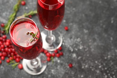 Photo of Tasty cranberry cocktail with rosemary in glasses on gray table, above view. Space for text