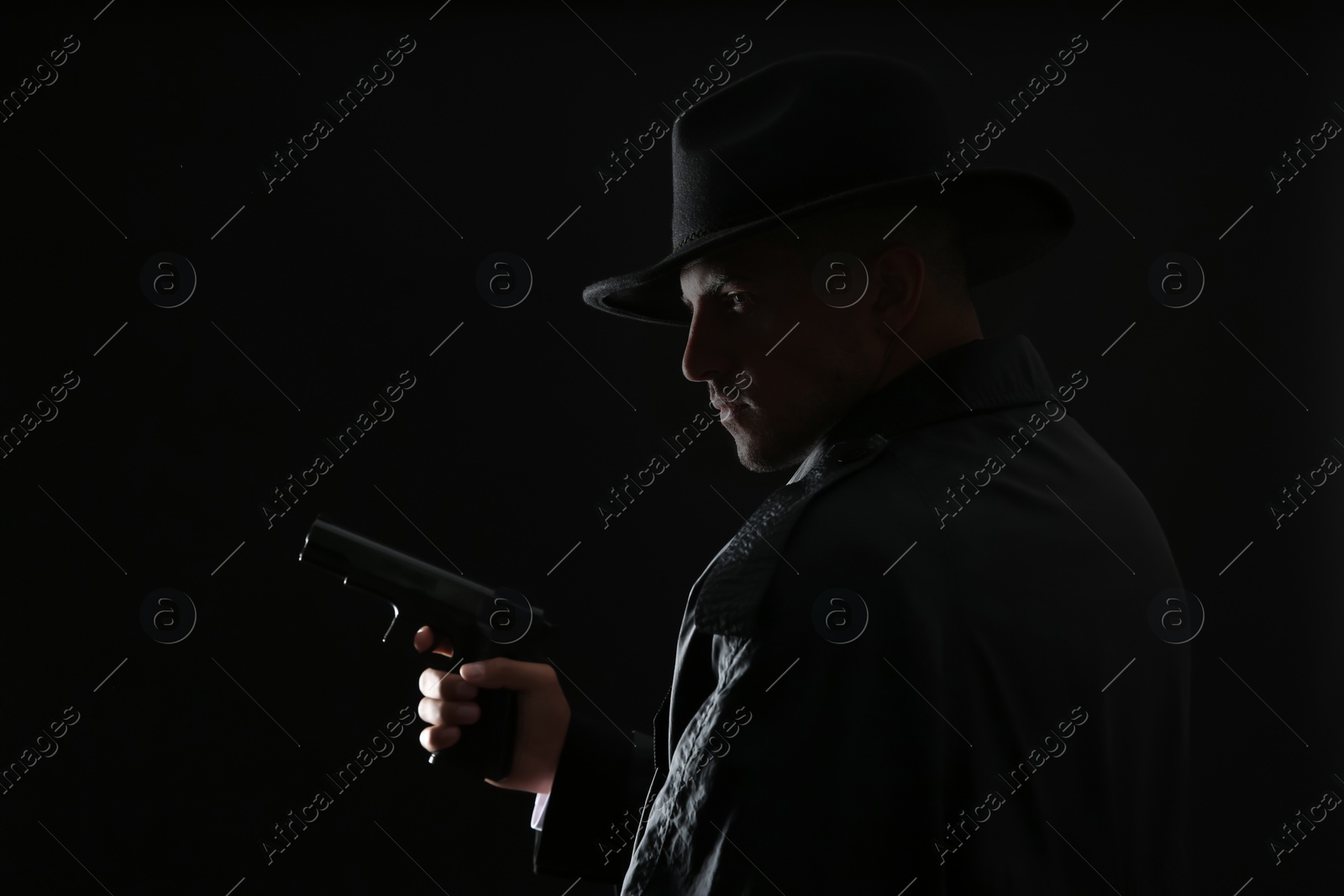 Photo of Old fashioned detective with gun on dark background