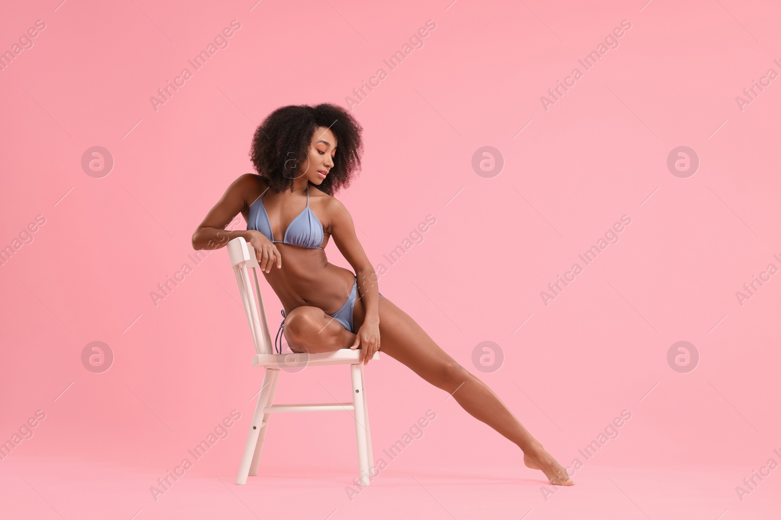 Photo of Beautiful woman in stylish bikini posing on chair against pink background