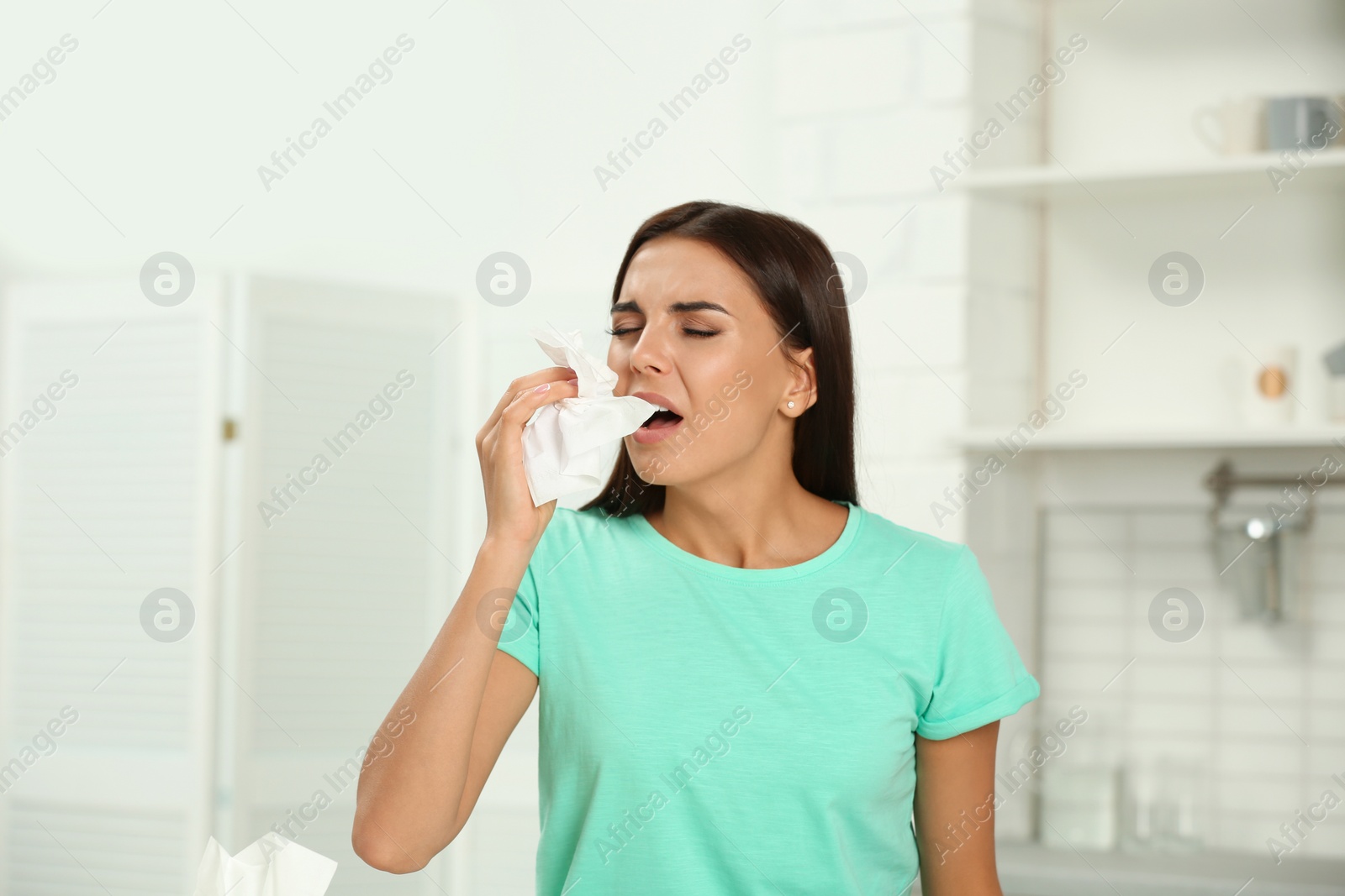 Photo of Young woman suffering from allergy in kitchen