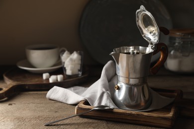 Brewed coffee in moka pot on wooden table, space for text