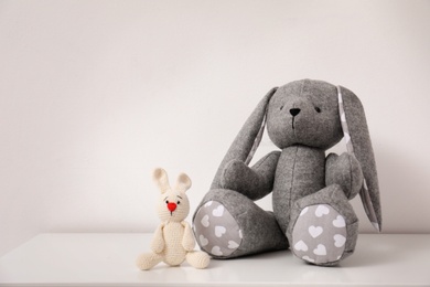 Photo of Toy rabbits on table near wall in child room. Space for text