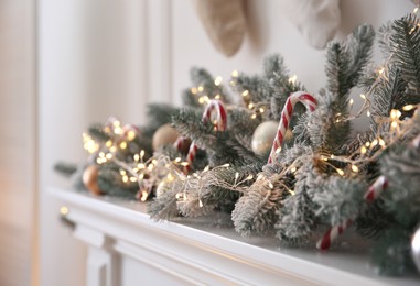 Beautiful decoration of fir tree branches, candy canes, fairy lights and Christmas balls in room, closeup