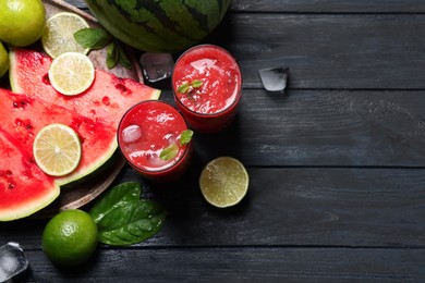 Glasses of delicious fresh watermelon juice, lime, mint and ice on black wooden table, flat lay. Space for text