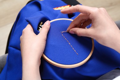 Photo of Woman with sewing needle and thread embroidering on cloth, closeup