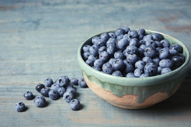 Photo of Crockery with juicy and fresh blueberries on wooden table. Space for text
