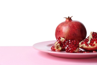 Photo of Plate with ripe pomegranates on table against white background, space for text