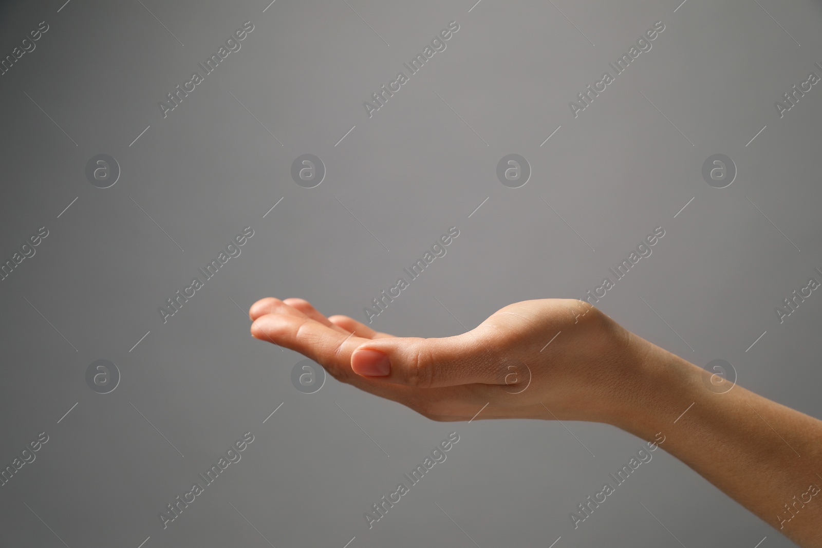 Photo of Woman holding something in hand on grey background, closeup. Space for text