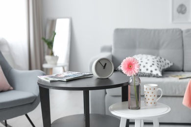 Photo of Stylish table with clock and magazines in living room