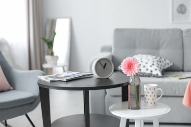 Stylish table with clock and magazines in living room