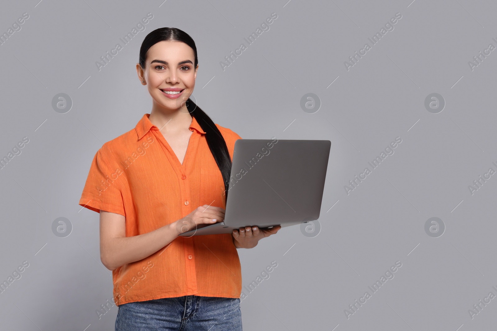 Photo of Happy woman with laptop on light gray background