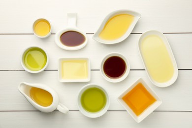 Photo of Vegetable fats. Different cooking oils on white wooden table, flat lay