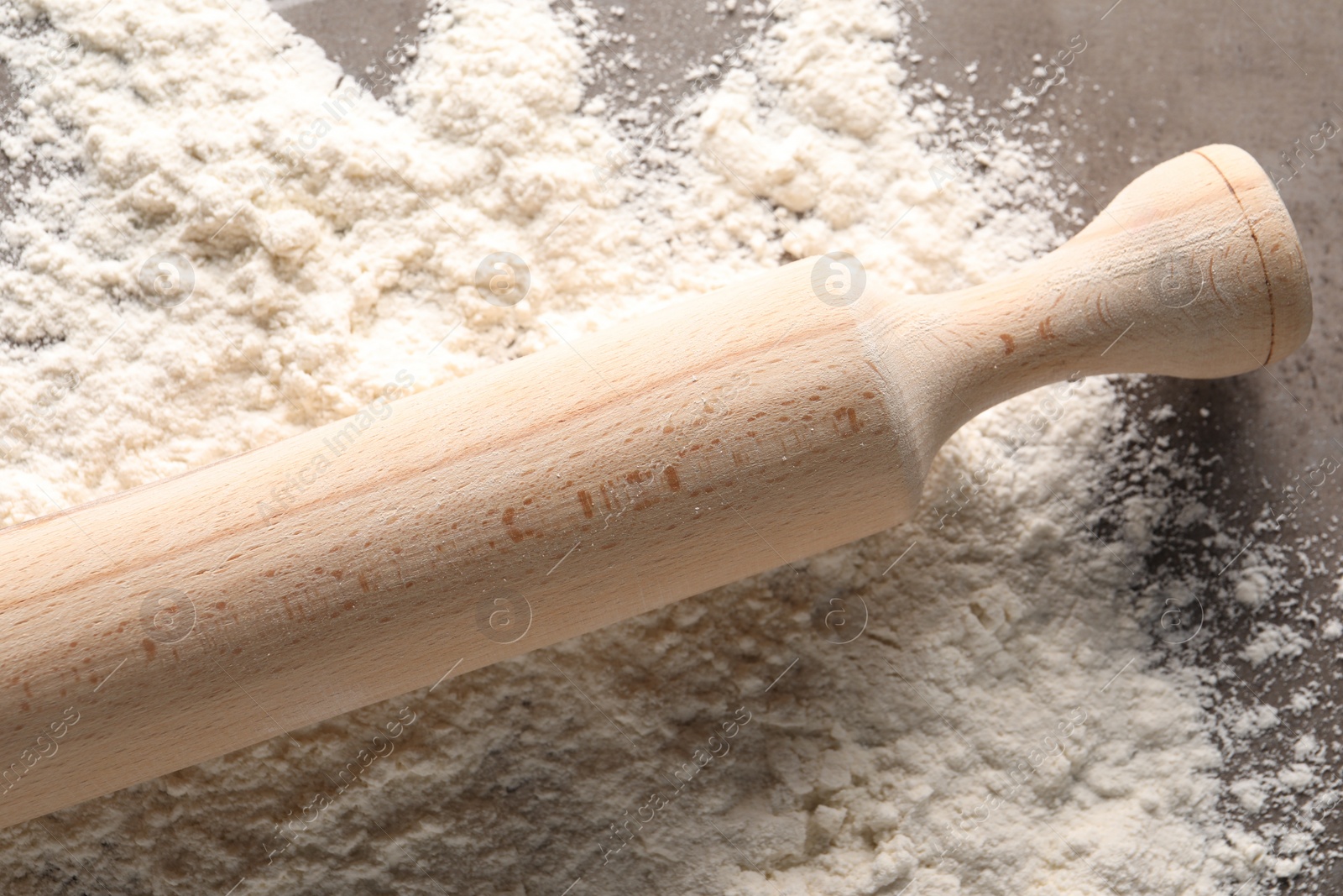 Photo of Scattered flour and rolling pin on grey textured table, top view