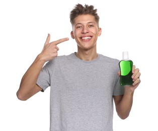 Photo of Young man with mouthwash pointing at his healthy teeth on white background