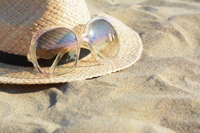 Photo of Hat with beautiful sunglasses on sandy beach. Space for text