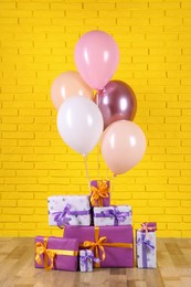 Many gift boxes and balloons near yellow brick wall