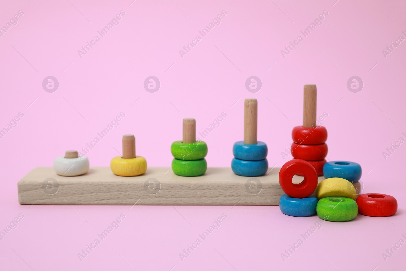 Photo of Stacking and counting game wooden pieces on pink background. Educational toy for motor skills development